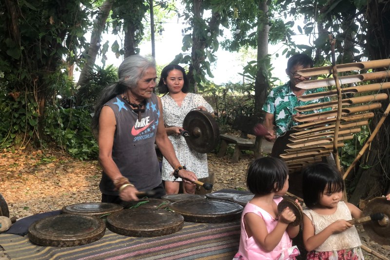 Les touristes vivent l'expérience de jouer du gong avec l'artisan A Biu 