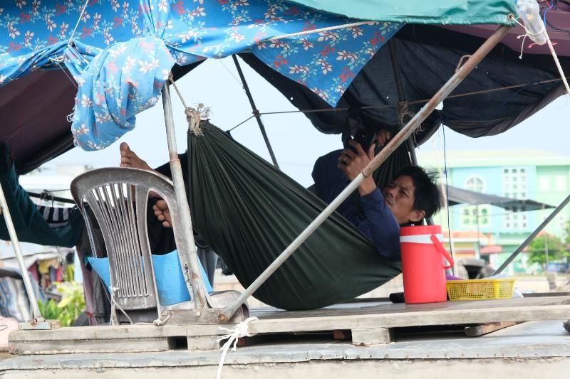 un homme regarde son phone sur le hamac dans son bateau
