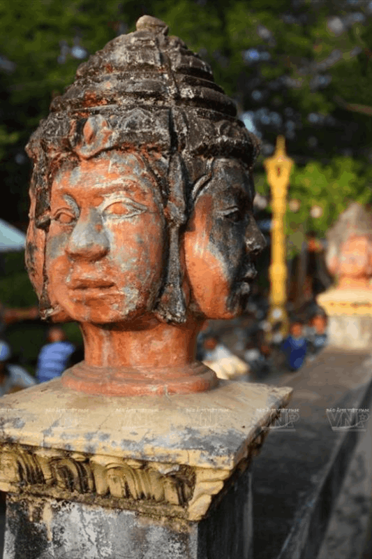 Tête à quatre visages du dieu Bayon sculptée sur les poteaux d’un temple Theravãda du bouddhisme vietnam, reflet du folklore khmer dans l’architecture sacrée.